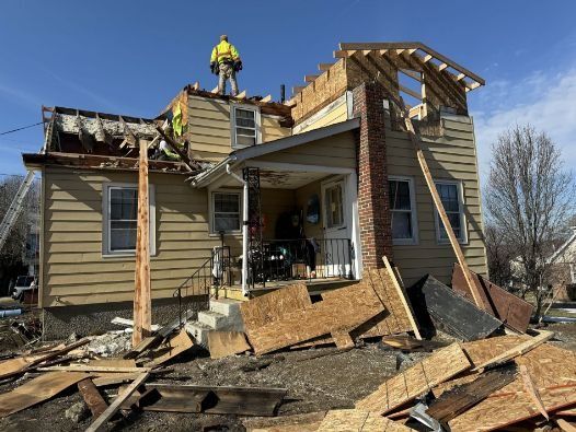 A house is being demolished and a pile of wood is in front of it.