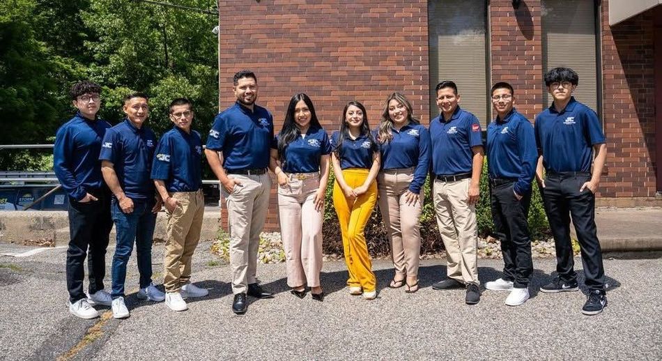 A group of people are posing for a picture in front of a brick building.