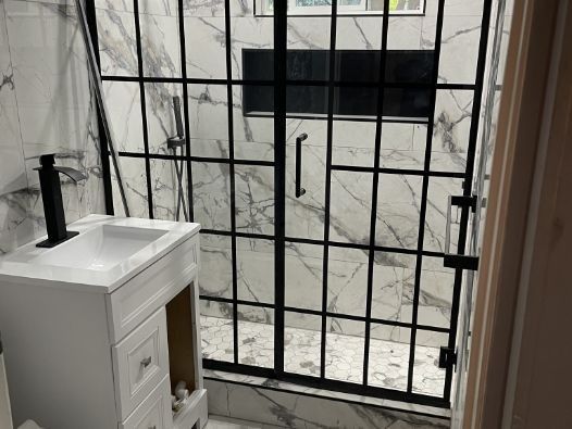 A bathroom with a sink and a walk in shower.