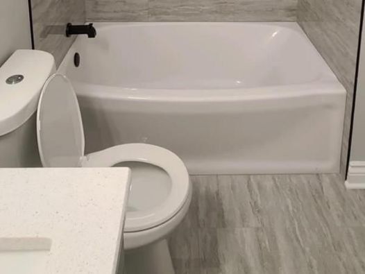 A bathroom with a toilet , sink and bathtub.