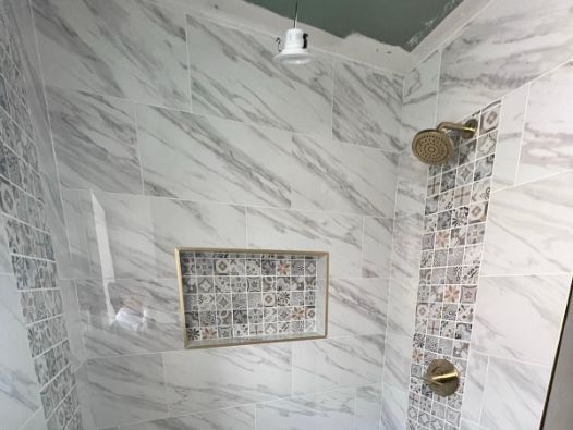 A shower with marble tiles and two shower heads.