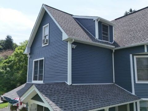 A blue house with a gray roof and white trim