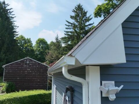 A blue house with a white gutter on the side
