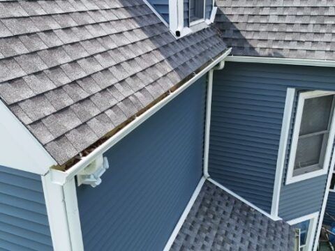 A blue house with a gutter on the side of it