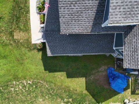 An aerial view of a house with a blue tarp on the ground.