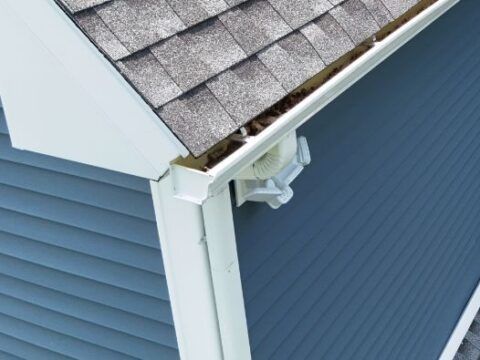 A blue house with a white gutter on the side