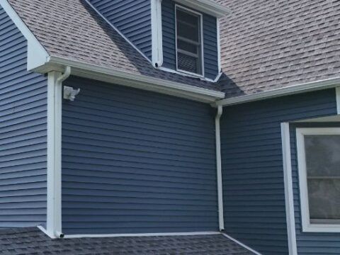 A blue house with a gray roof and white trim.