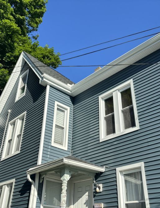 A blue house with white trim and a blue sky in the background
