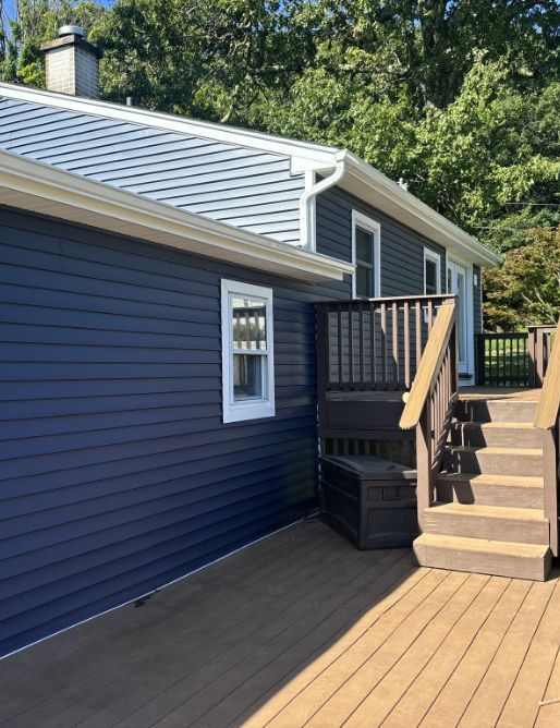 A blue house with a deck and stairs leading to it