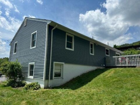 A large house with a lot of windows is sitting on top of a grassy hill.