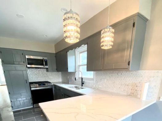 A kitchen with gray cabinets and white counter tops