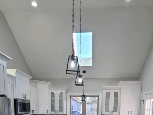 A kitchen with white cabinets and stainless steel appliances and a skylight in the ceiling.