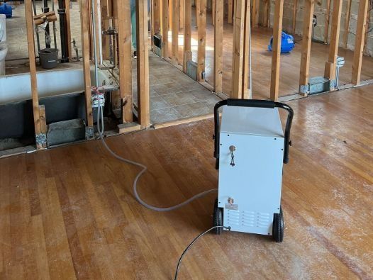 A machine is sitting on a wooden floor in a room under construction.
