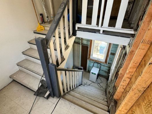 A staircase with a wooden railing going up to the second floor of a building.