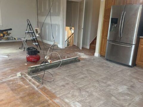 A stainless steel refrigerator is sitting in a kitchen under construction.