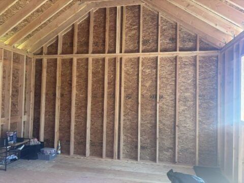 A room that is being built with wooden walls and a vaulted ceiling.