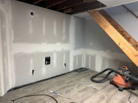 A vacuum cleaner is sitting in a room under a staircase.