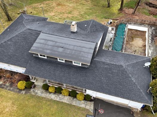 An aerial view of a house with a black roof and a pool.