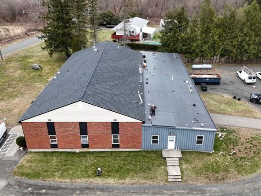 An aerial view of a large brick building with a black roof