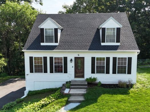 A white house with black shutters and a black roof
