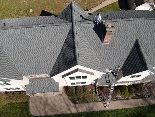 An aerial view of a house with a man standing on the roof.