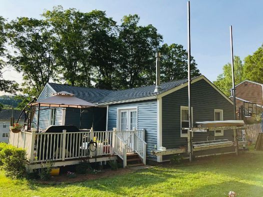 A small blue house with a deck and umbrella in front of it.