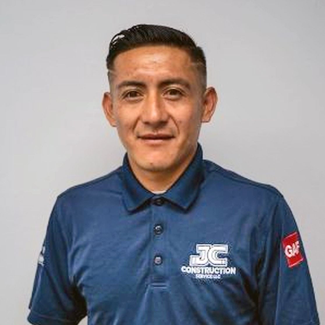 A man in a grey shirt is smiling for the camera
