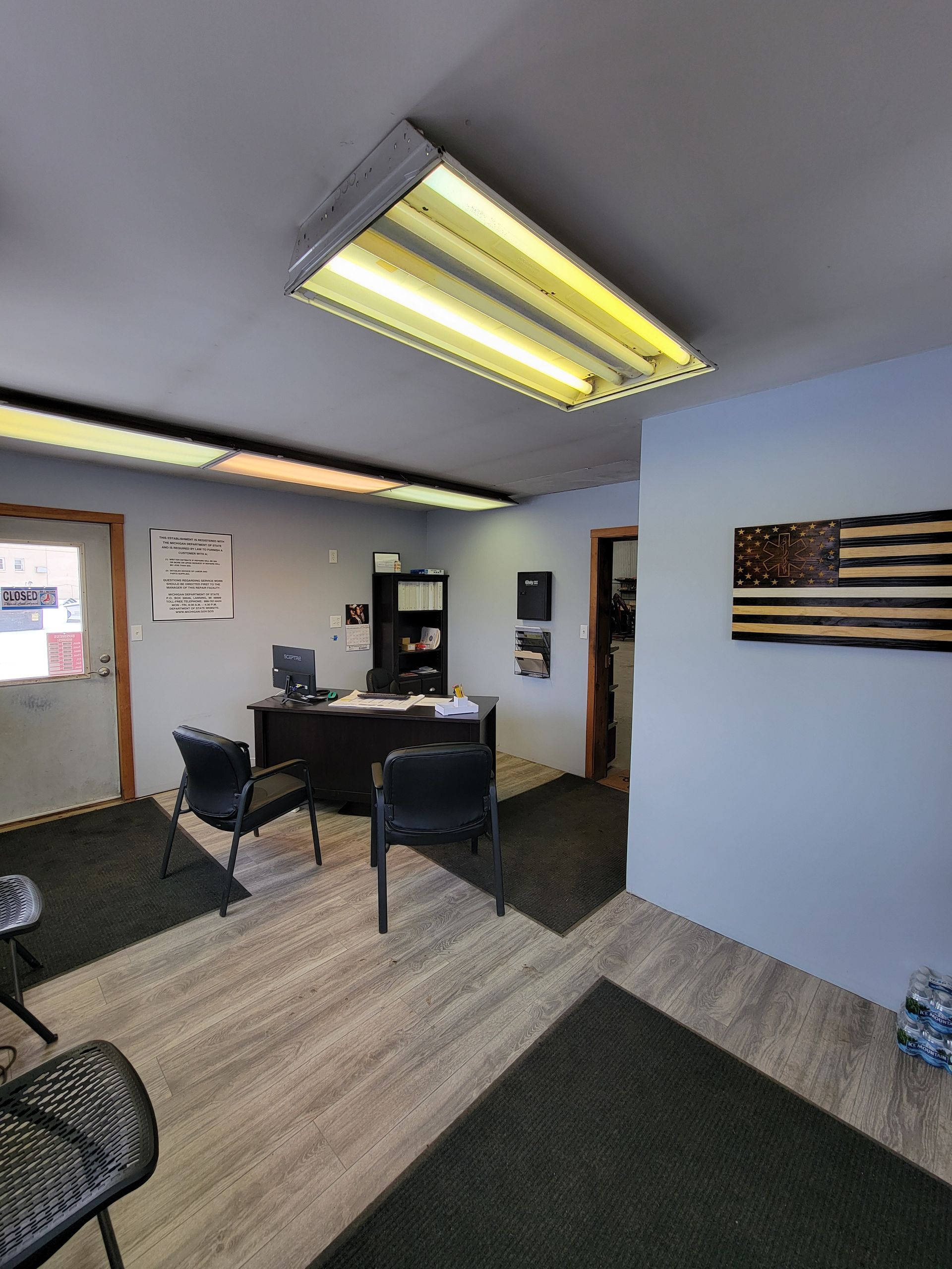 A room with a desk , chairs , and an american flag on the wall.