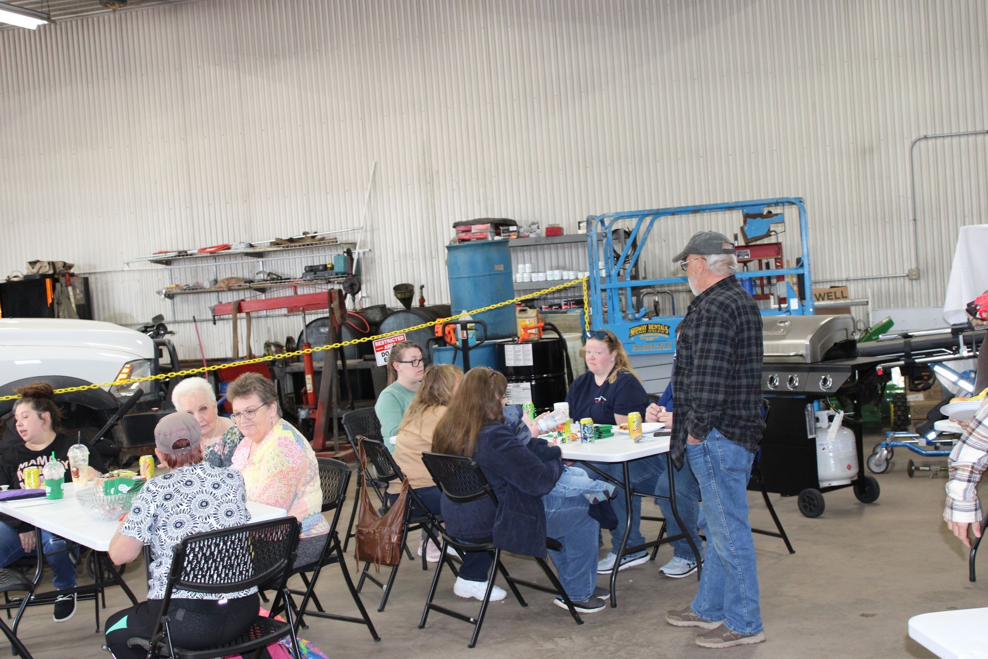 A group of people are sitting at tables in a garage.