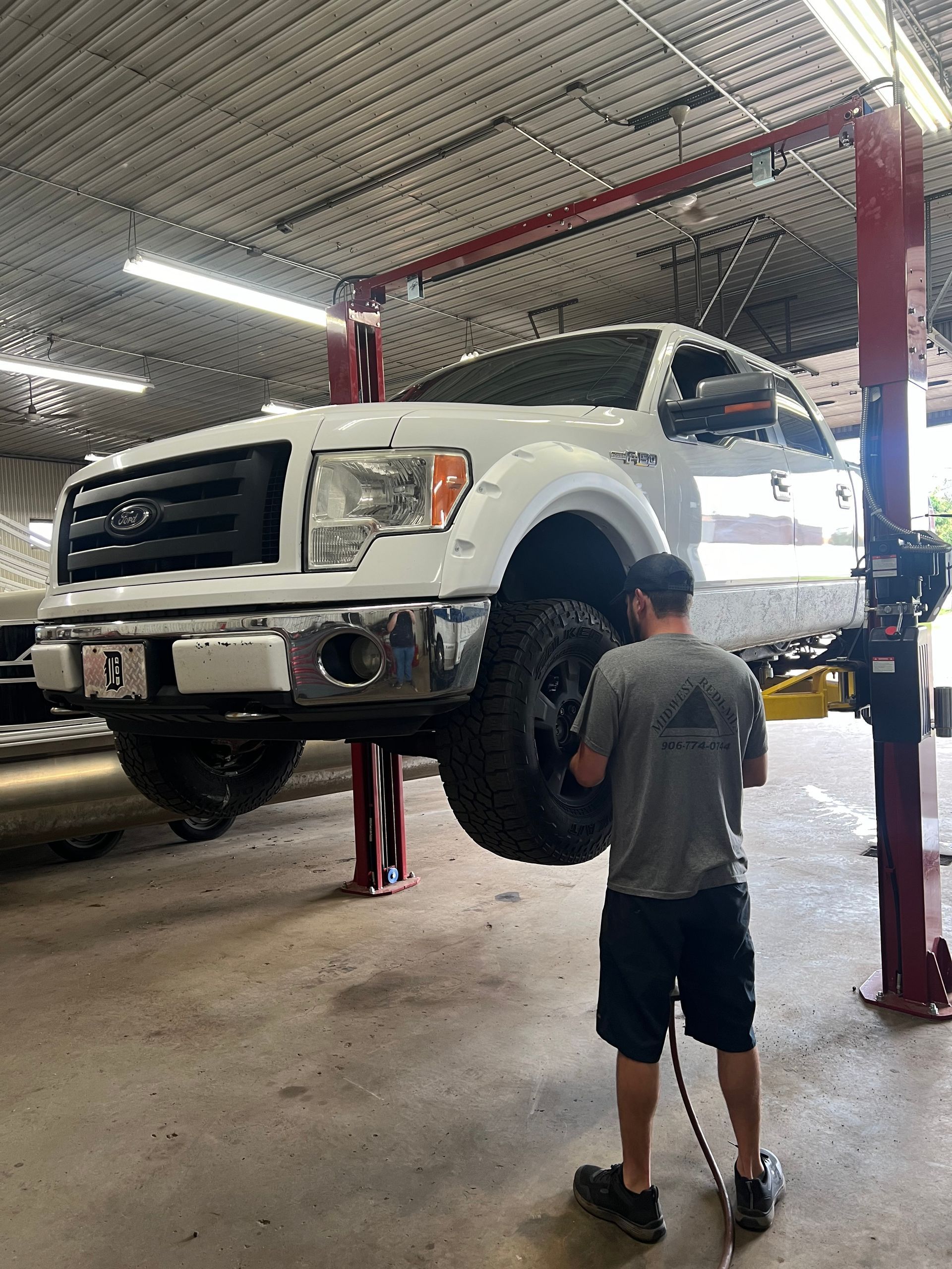 A man is working on a truck on a lift in a garage.