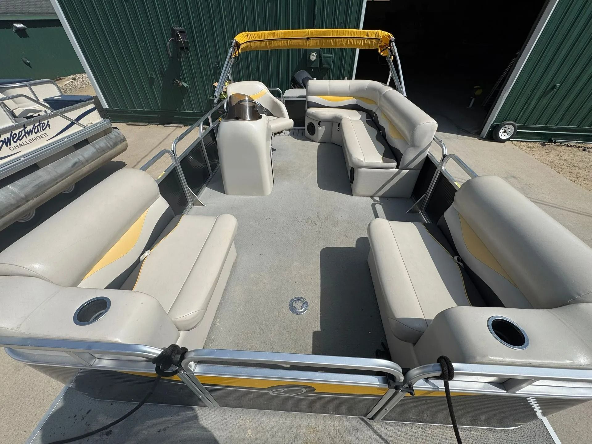 Open pontoon boat interior with gray seating and tan trim, viewed from the stern.