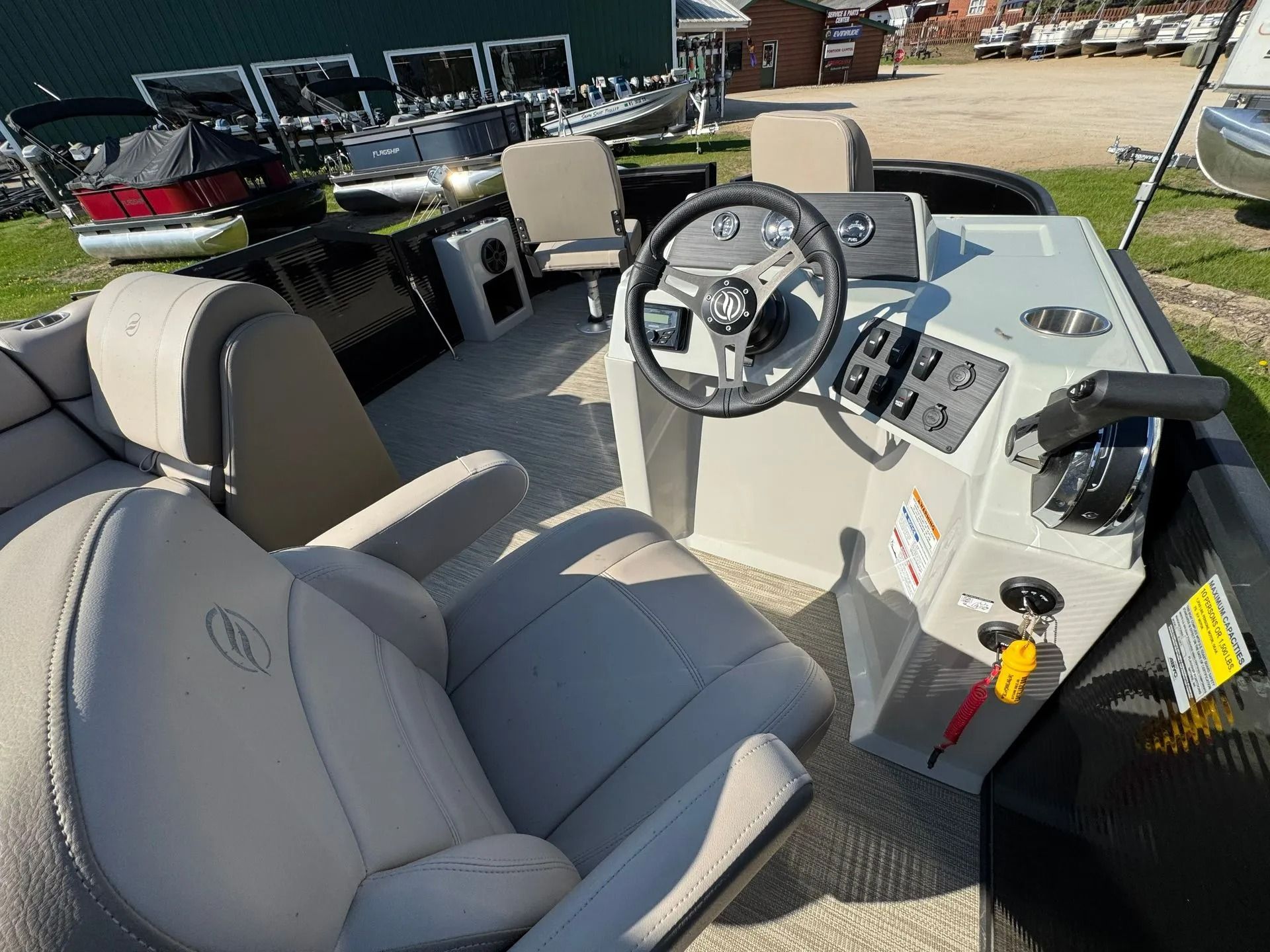 Boat cockpit with gray seats, steering wheel, and controls on a trailer outdoors.