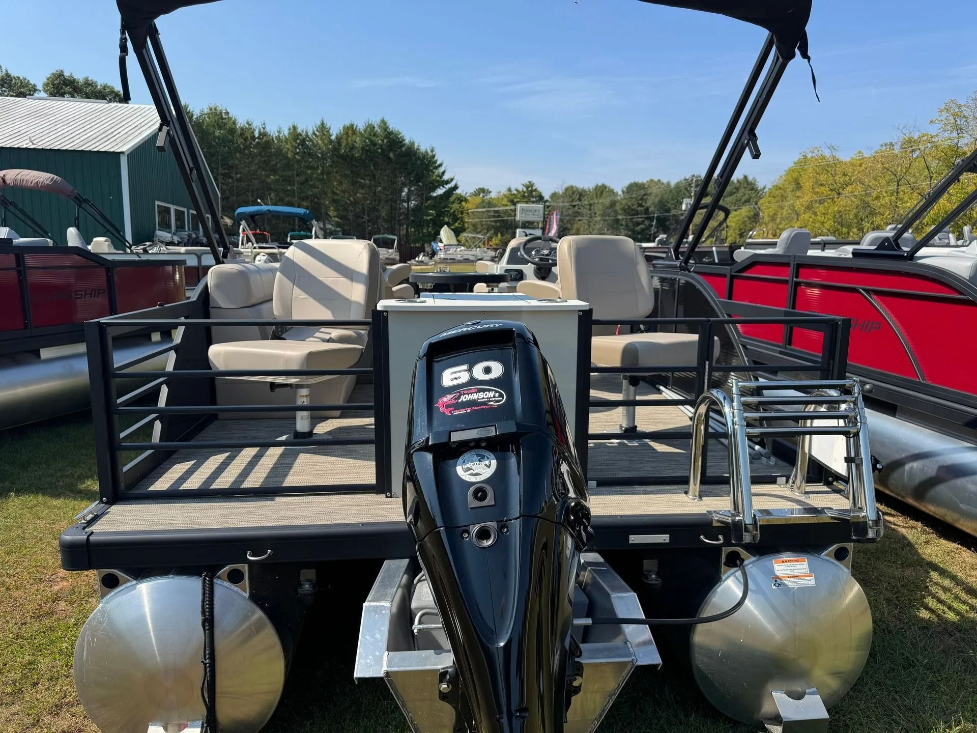 Pontoon boat stern with twin outboard motors and cushioned seats on a calm lake