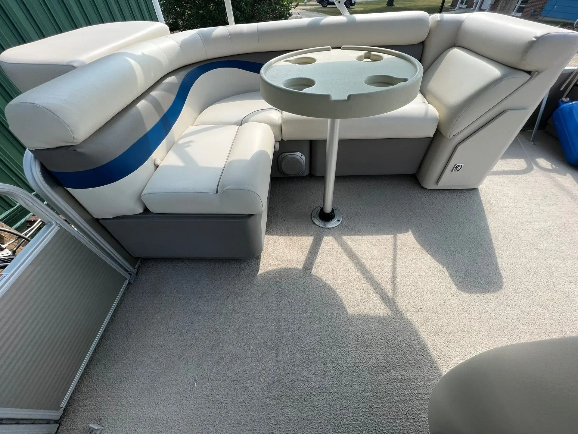 White cushioned boat seating around a round glass table on a carpeted deck in the sun