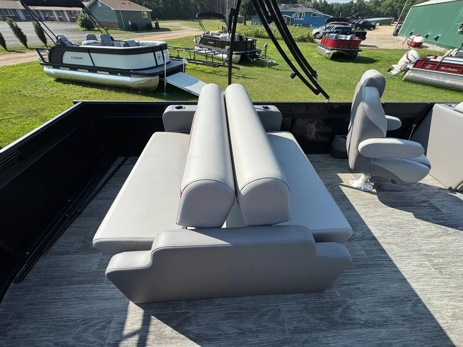 Gray boat seats and cushions on a truck bed, with other boats and grass in the background.
