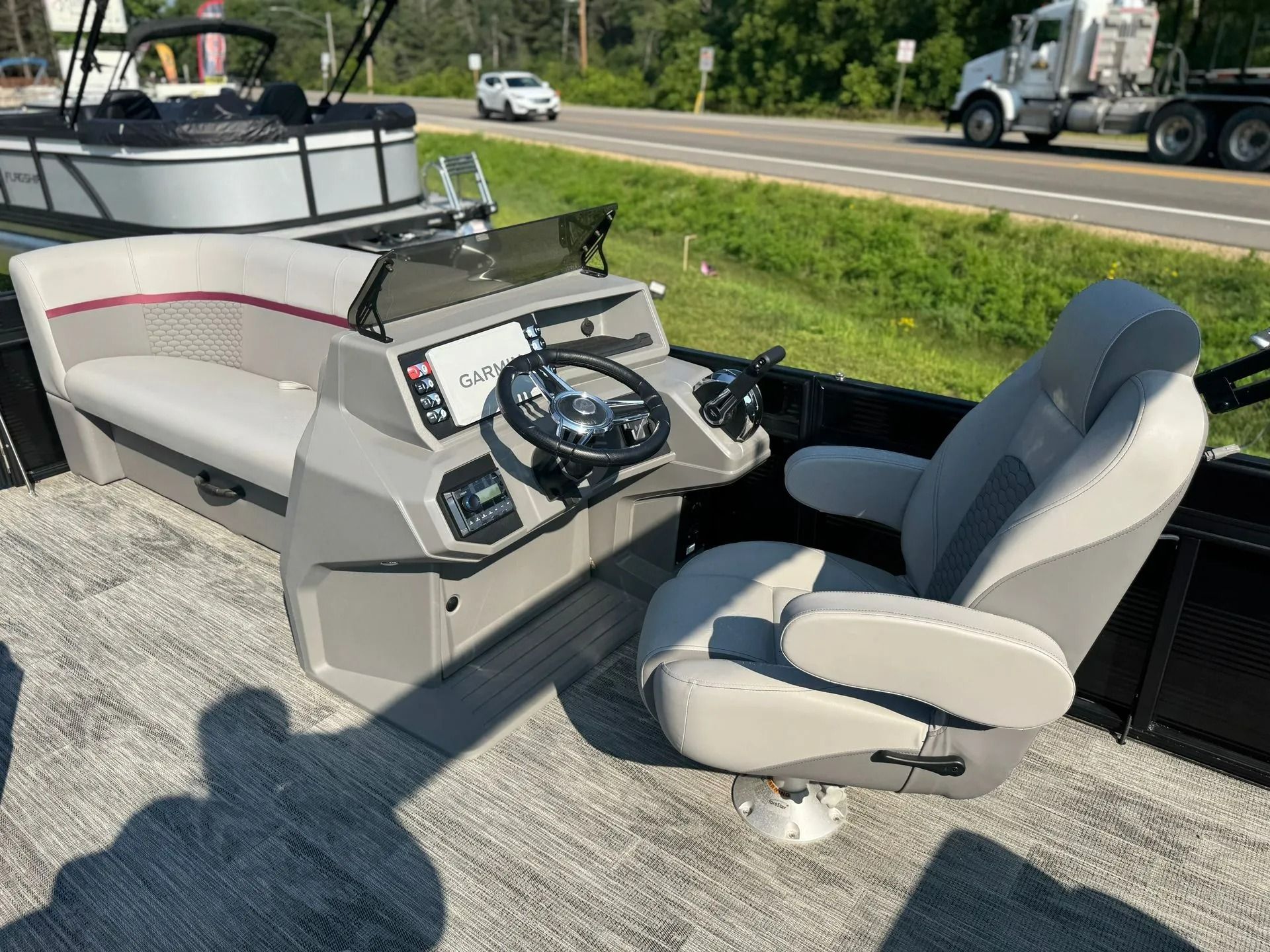 Boat helm seat and steering console on a pontoon boat by a roadside.