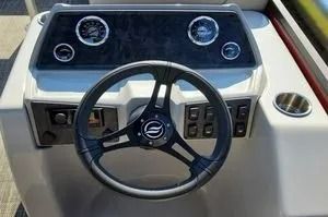 Boat helm with steering wheel, gauges, and control panel in a white console.