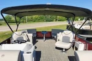 Boating deck with white seating under a black canopy, overlooking a lakeside view