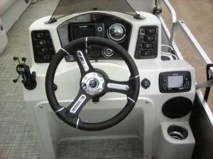 Boat helm with steering wheel, gauges, throttle lever, and cup holders in a white console