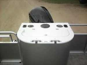 White control console on a boat deck with dials and a black wheel behind it