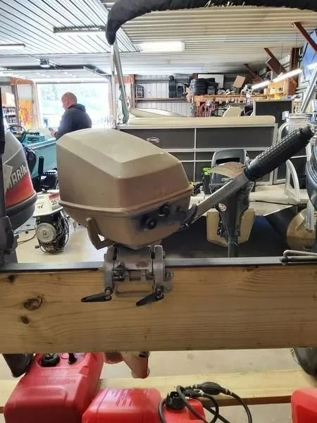 Tan RC helicopter on a workbench in a garage, with tools and equipment in the background.