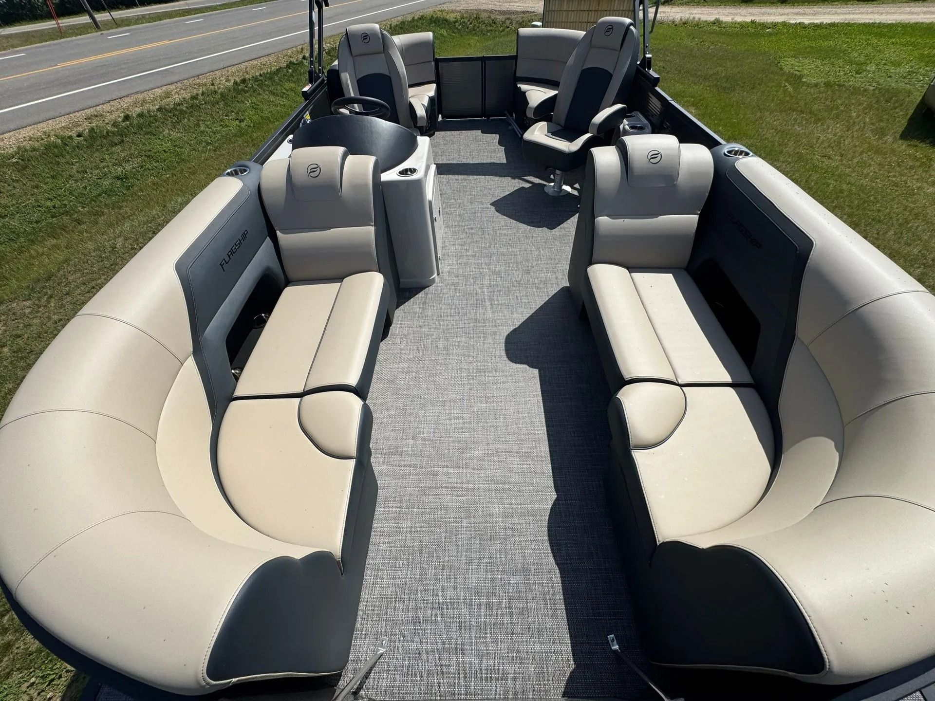 Empty beige and gray boat cockpit with wraparound bench seating on a sunny day