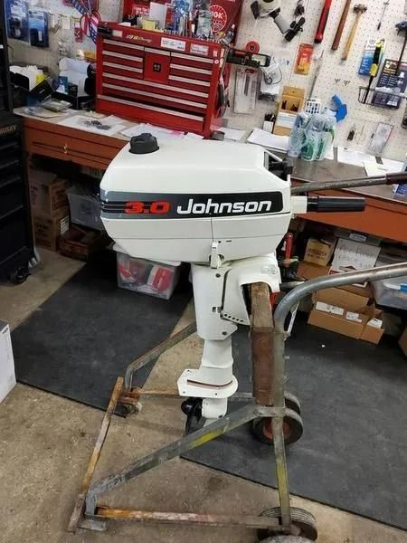 Johnson 3.0 outboard motor mounted on a stand in a workshop garage.