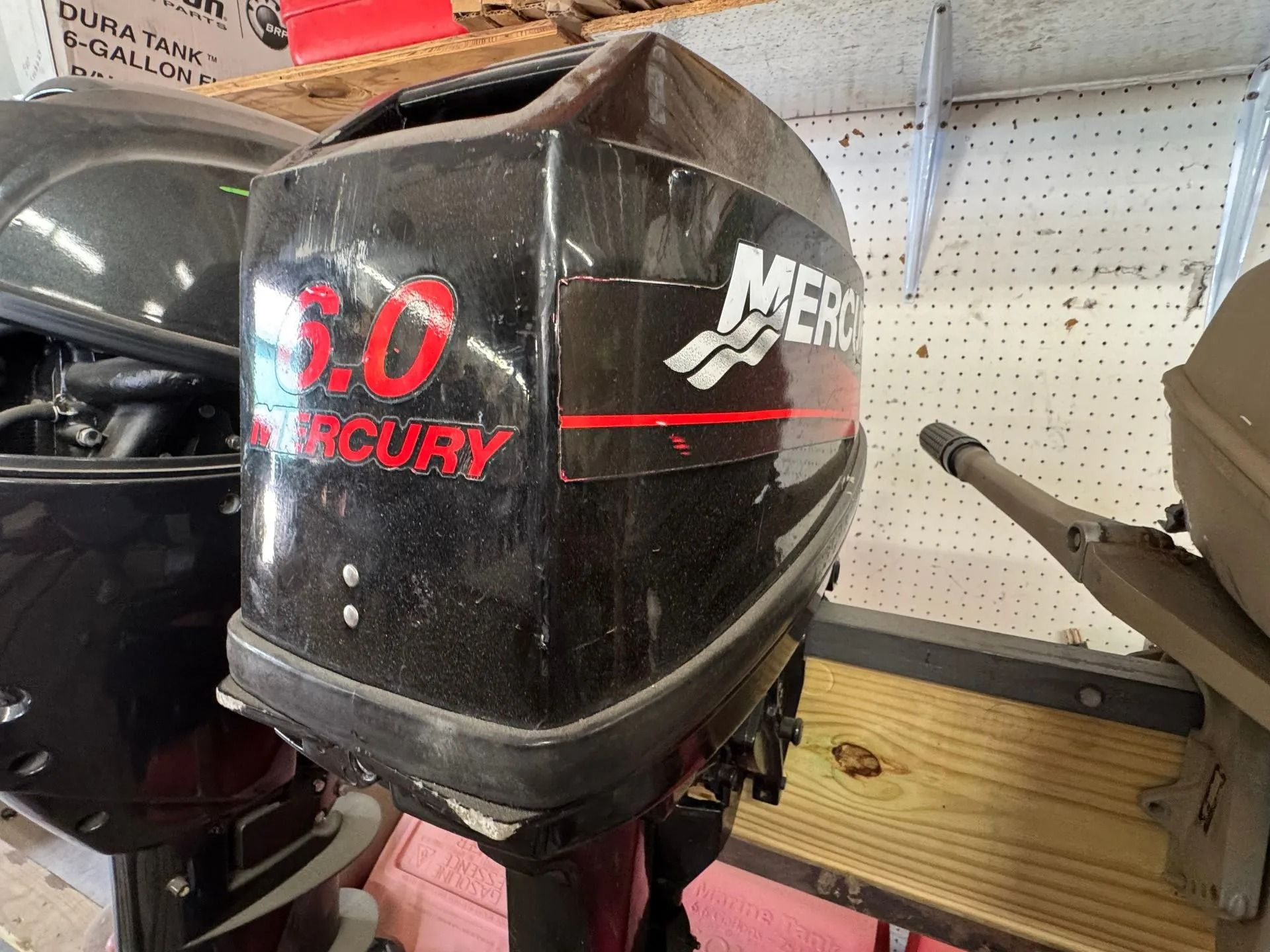 Black Mercury 3.0 outboard motor with red lettering on a showroom shelf