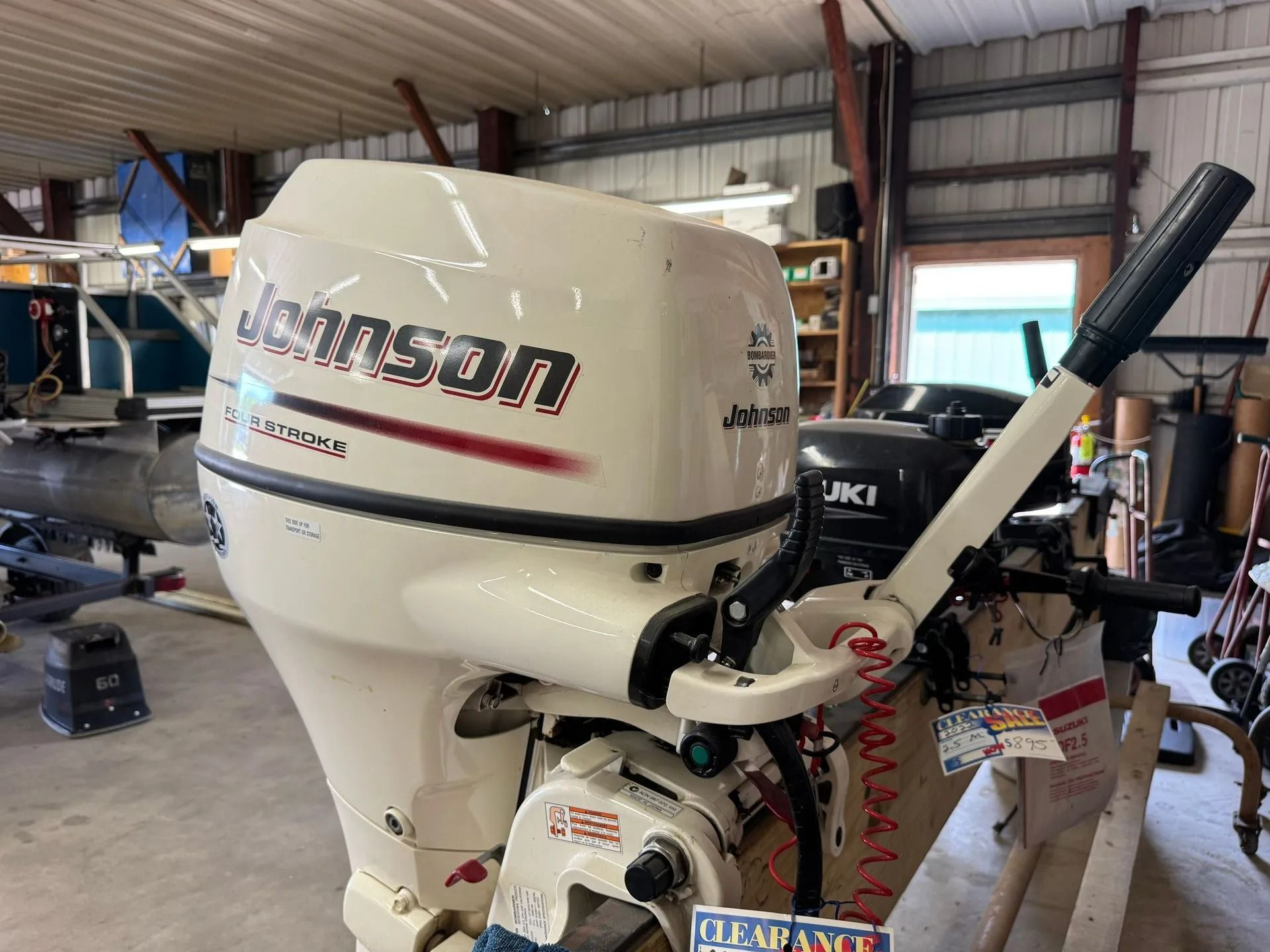 White Johnson outboard motor mounted on a boat, shown in a workshop garage.