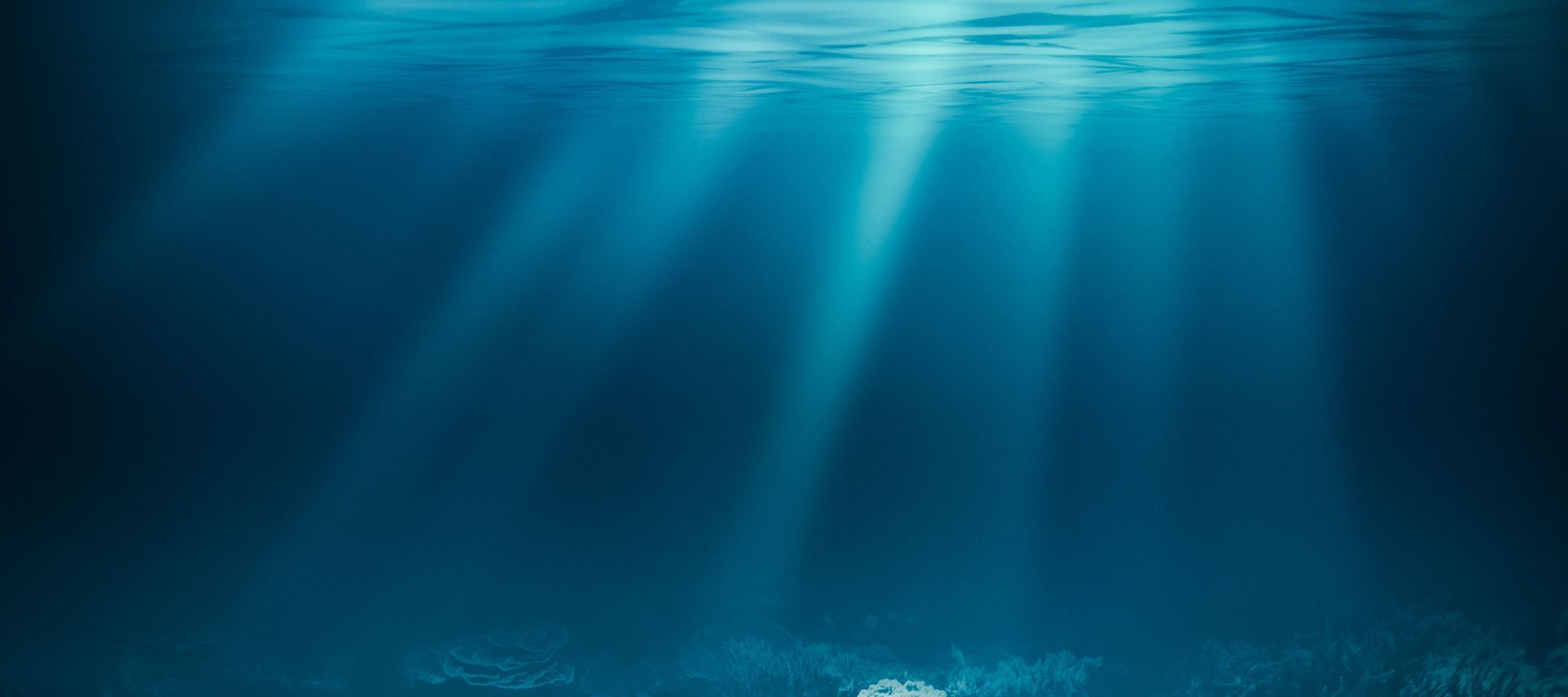 Blue underwater scene with sunbeams streaming through the water surface