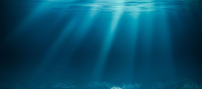Blue underwater scene with sunbeams streaming through the water surface