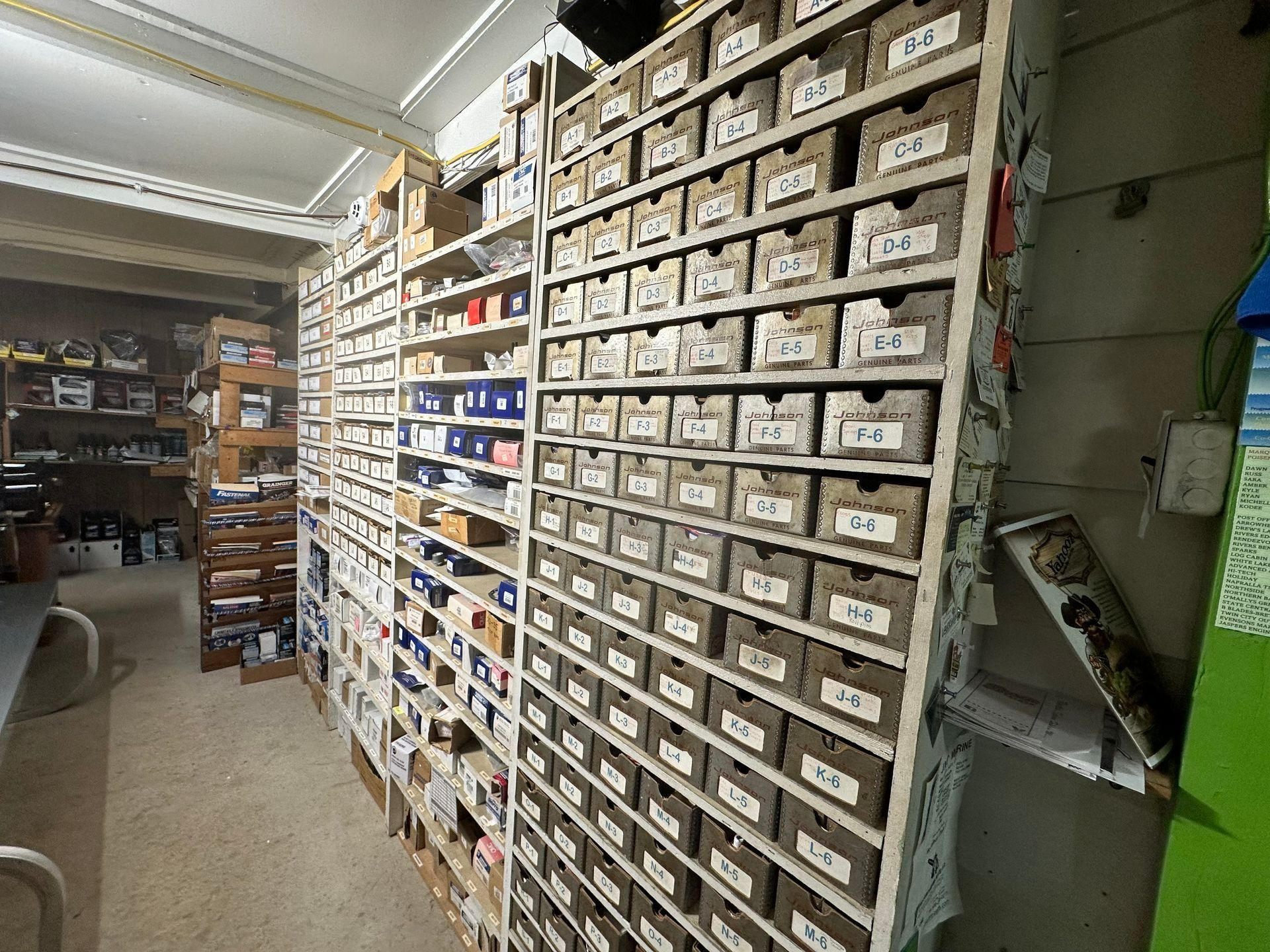 Storage aisle with shelves of labeled parts drawers and bins in an industrial workspace