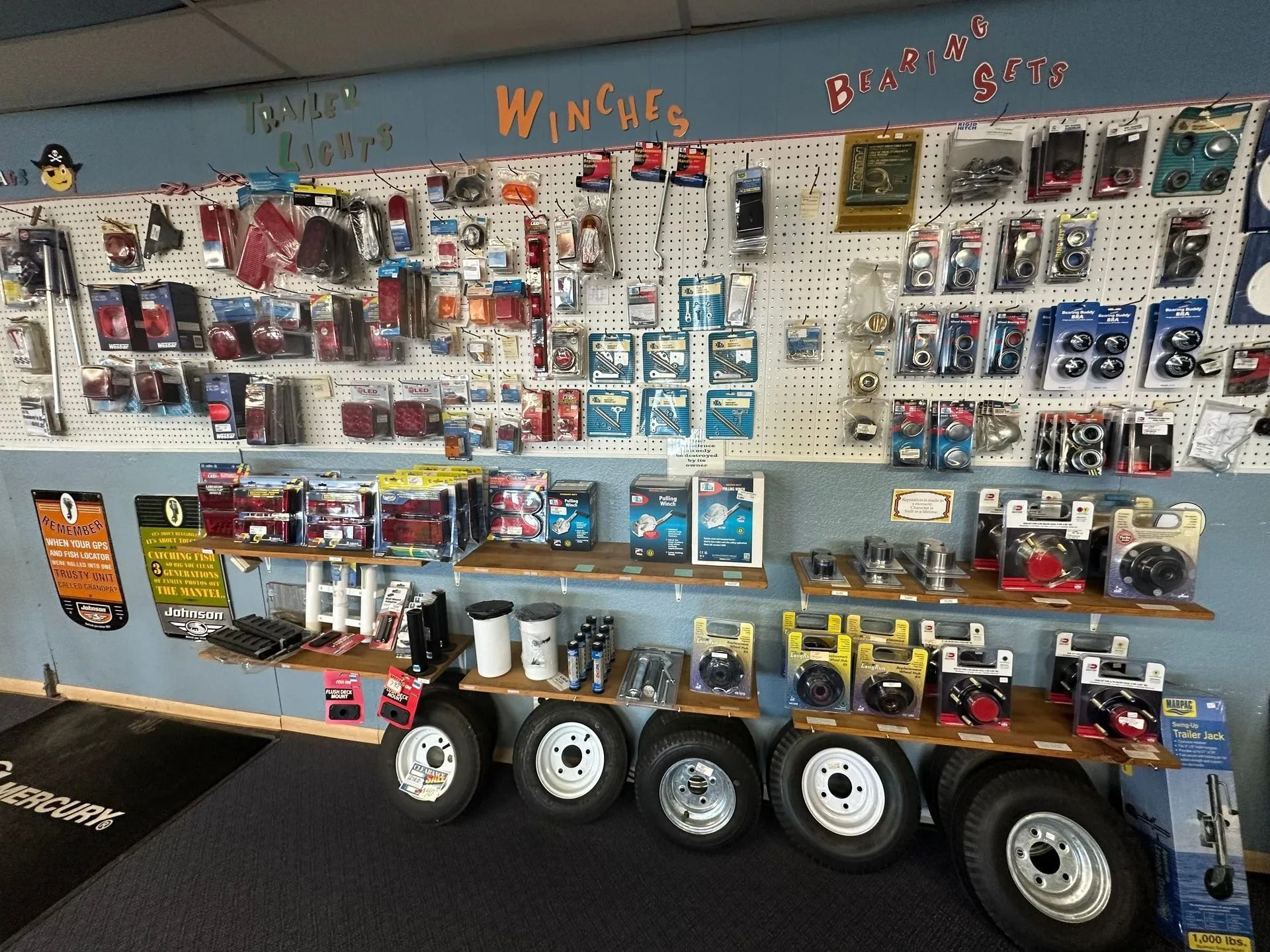 Display wall of remote-control parts and accessories with shelves and toy car tires in a hobby shop.