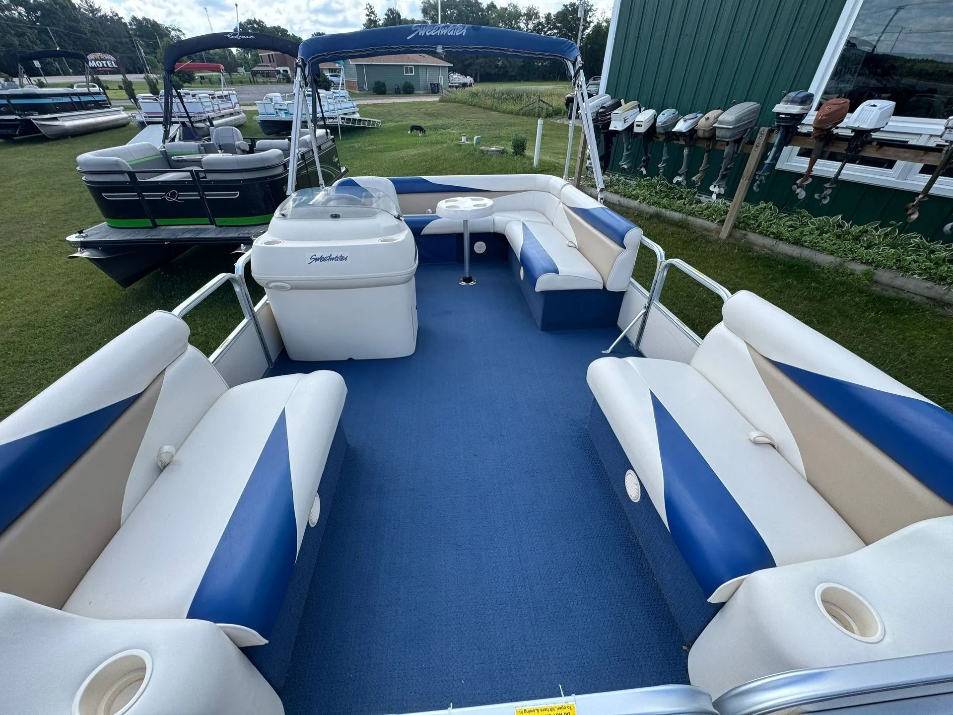 Pontoon boat interior with blue carpet and white seats at a marina dock